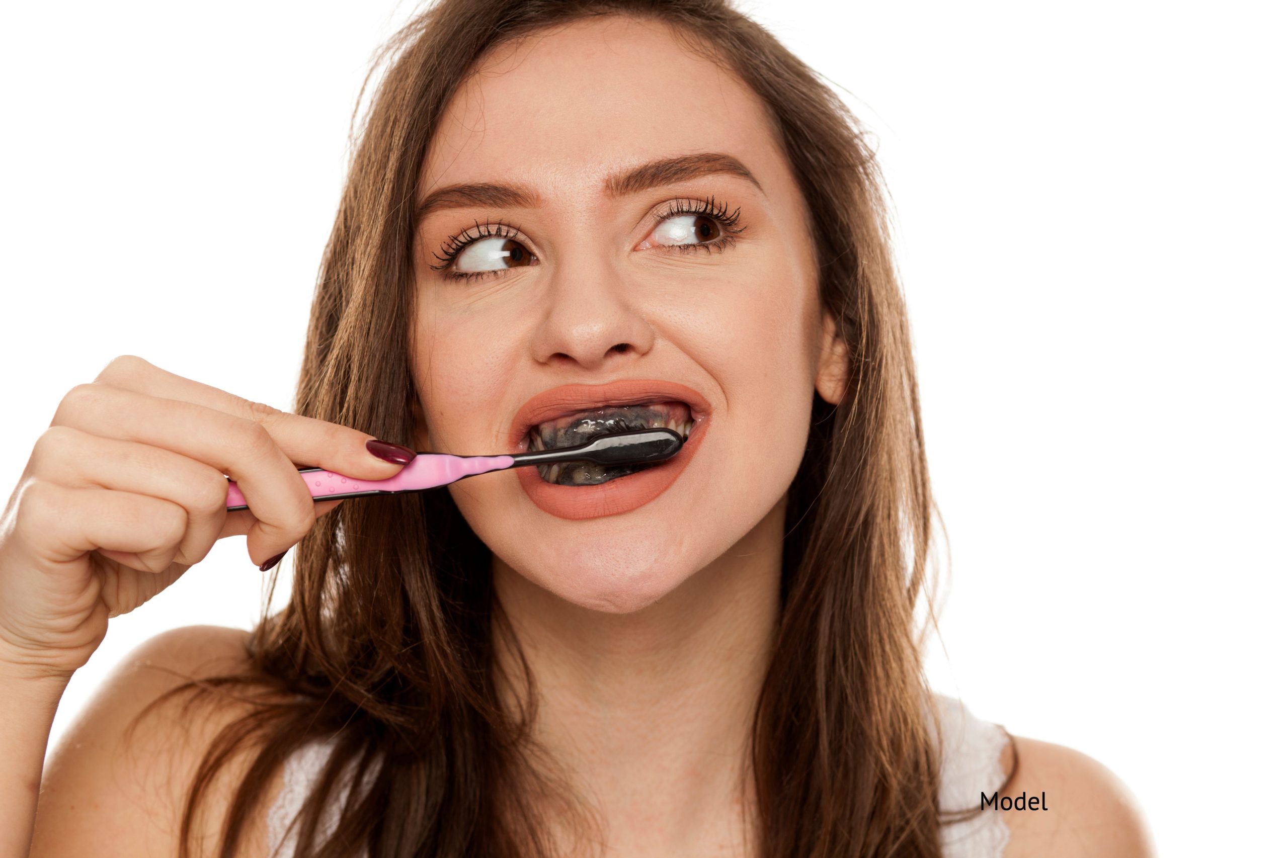Woman brushing her teeth with charcoal