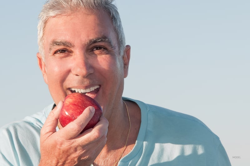 Middle-aged man preparing to eat an apple.