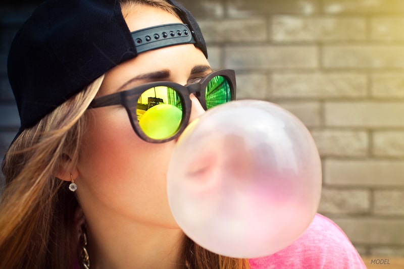 Young woman blowing a bubble out of chewing gum.